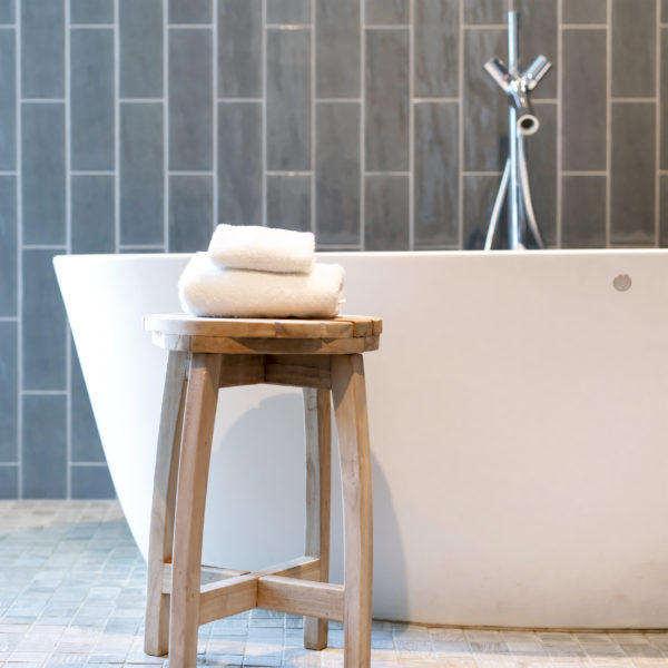 Freestanding bathtub in modern bathroom with grey subway tile