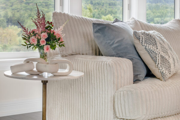 Brass and marble side table with flowers and a corduroy sofa